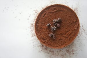 Top view of a rich chocolate dessert dusted with cocoa powder on a white background.